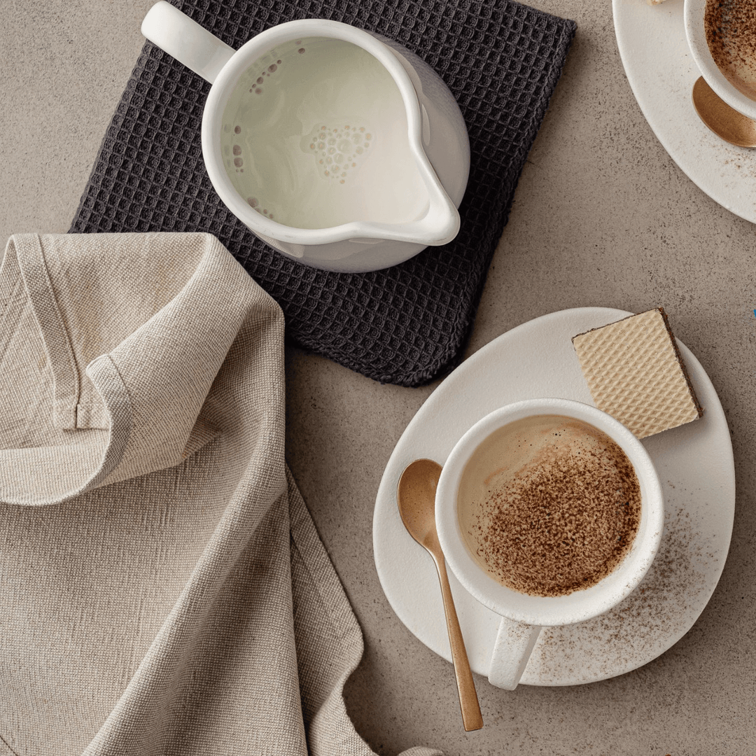 Coffee with creamer with wafer, table cloth and spoons